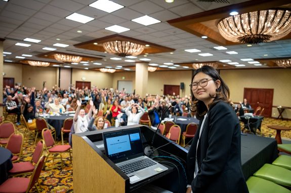 A woman is in front of a podium at a conference