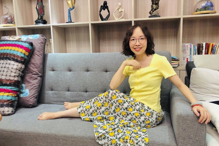 A woman sitting barefoot on a couch.