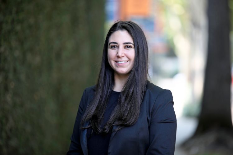 A headshot of a woman in front of a wall of greenery