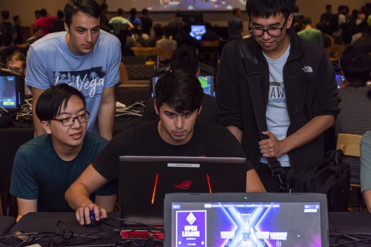 students gather around a computer to play eSports