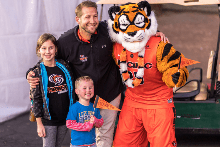 the powercat mascot poses for a picture with a man and two children