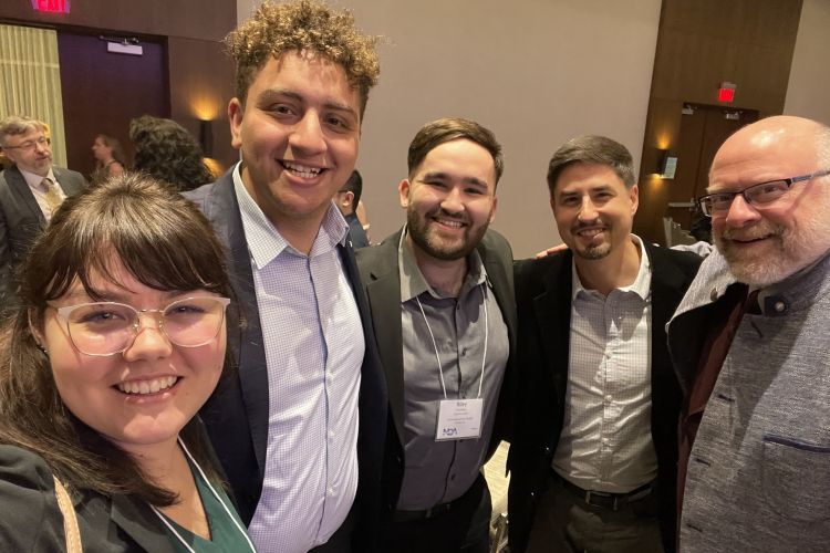 three students and two professors pose for a group photo