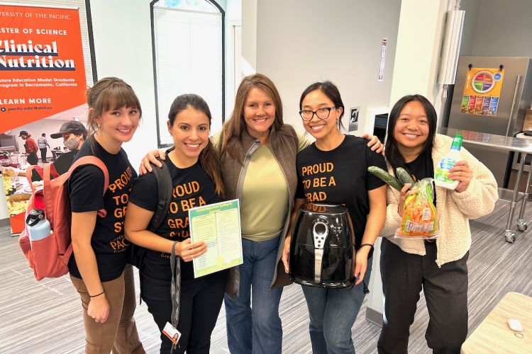 five women stand together smiling at the camera