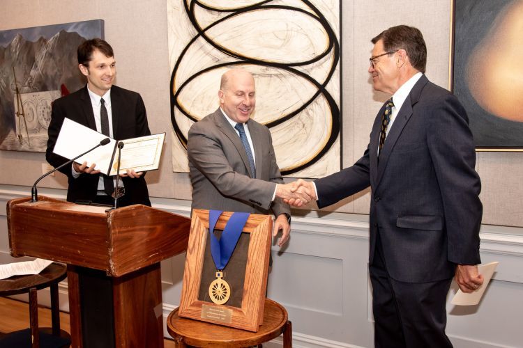 McCaffrey shaking hands with an individual to accept an award.