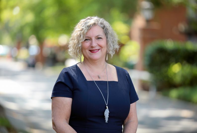 A portrait of Mindy Danovaro in front of a background of blurred greenery