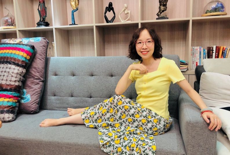 A woman sitting barefoot on a couch.