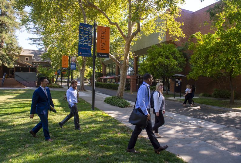 Four students walk across campus