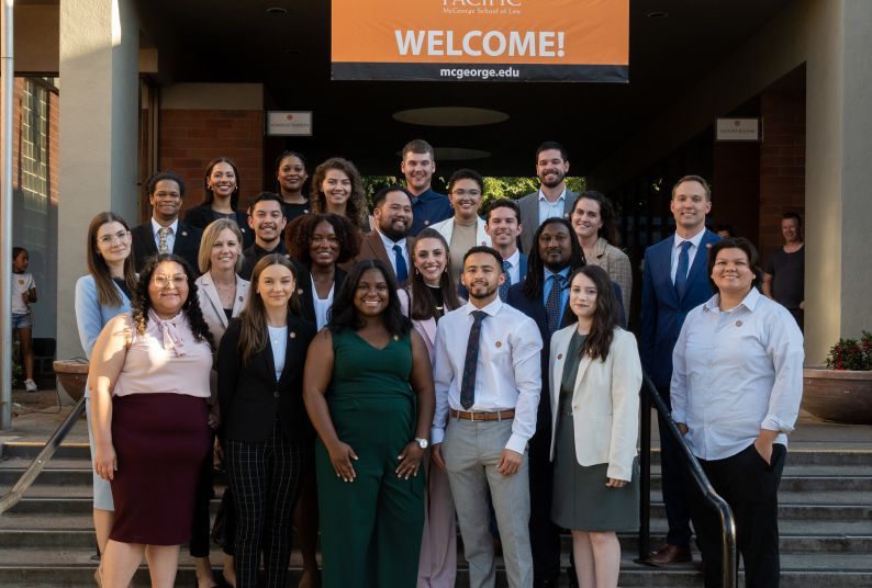 A group of 23 students pose on the steps of a staircase outdoors