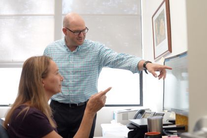 two staff members look at a computer