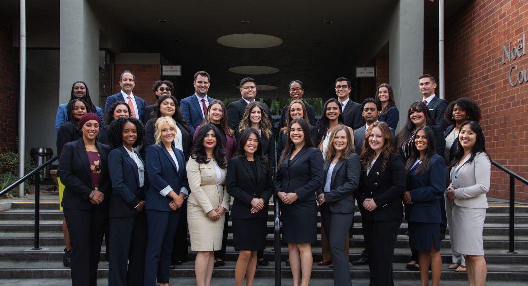 A group photo of 30 people pose for a photo outside. 