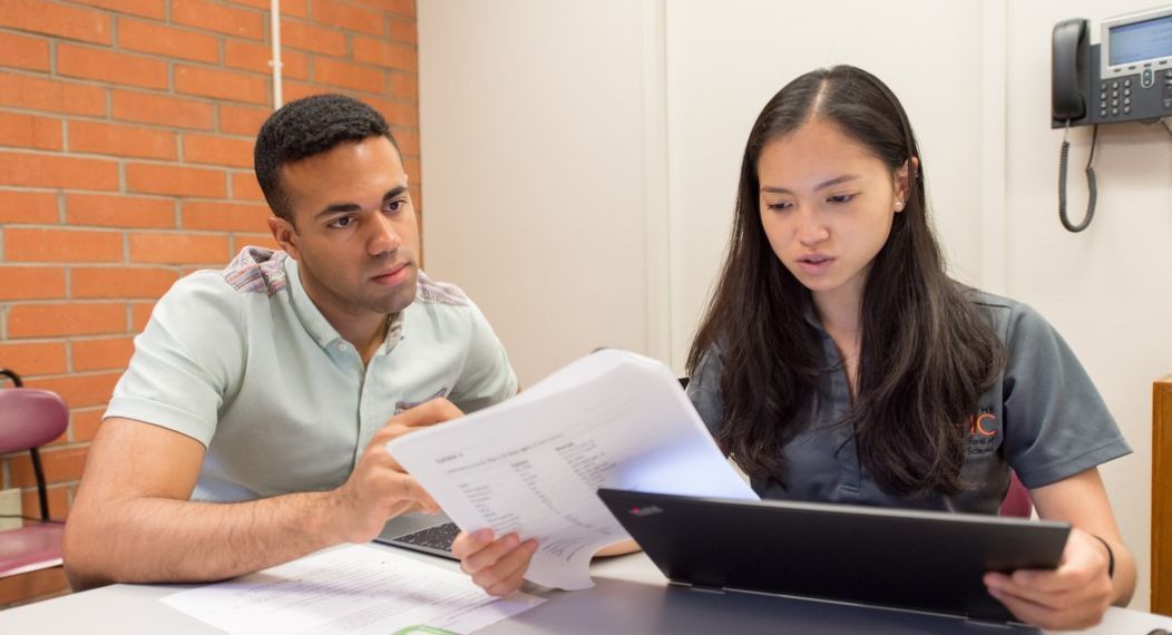 Photos shows two Pacific PA students looking at the screen on a laptop. 