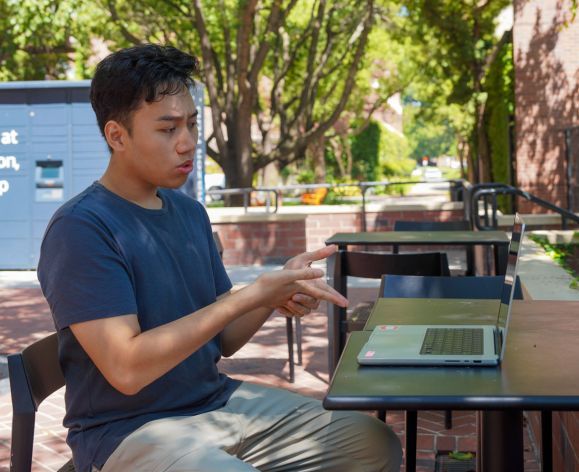 Student on campus using his laptop for a video call.