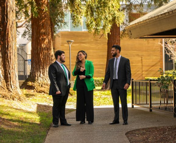 3 students standing on a walk pathway at McGeorge School of Law