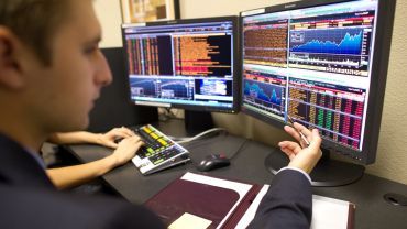 student looking at a screen analyzing stocks